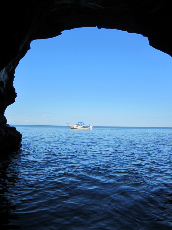Photo: Boston Whaler boat CONTINUOUSWAVE framed by arch of a sea cave on the north side of Devils Island, Apostle Islands, Lake Superior, Wisconsin.
