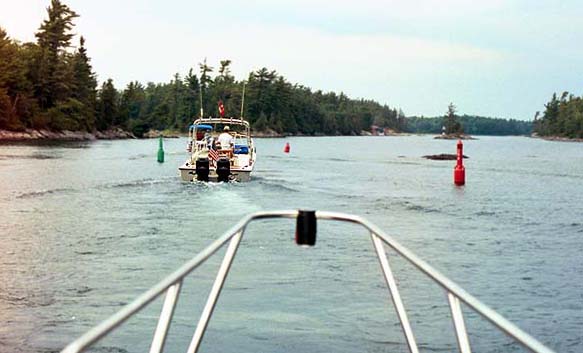 [Photo: Whalers navigating narrow channel marked by buoys.]