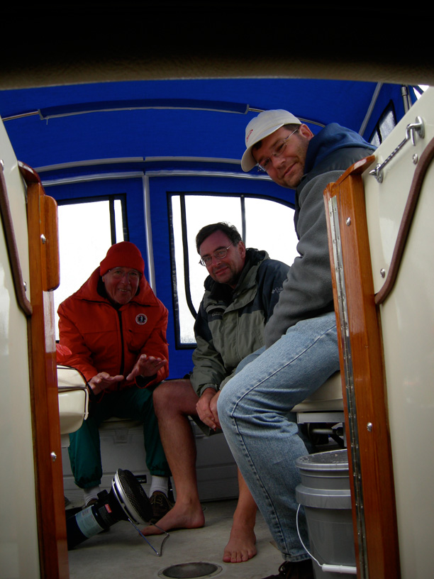 Photo: Interior of Boston Whaler REVENGE 22 with crew huddle around propane heater on cockpit deck.
