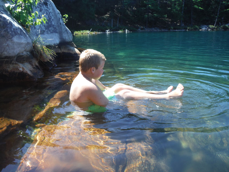 Young swimmer rests on rock ledge at Topaz Lake