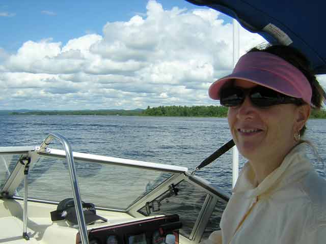 Photo: Chris at the helm of CONTINUOUSWAVE with the Laurential foothills of Quebec in the background.