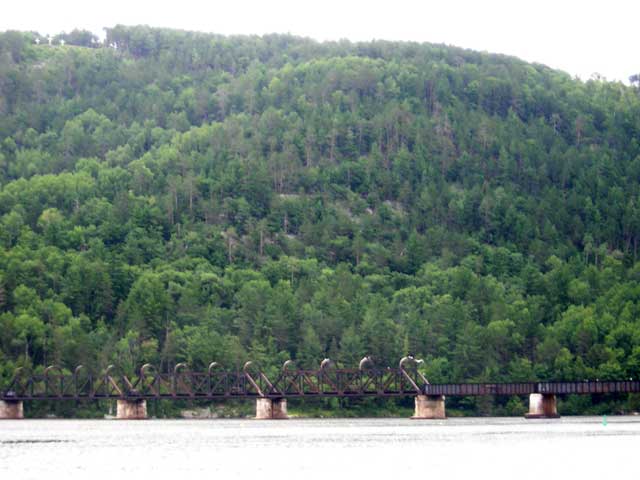 Photo: Trestle crossing river and three crosses on top of hill.