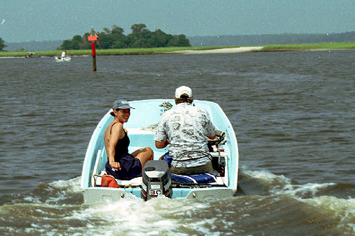 [Photo: Boston Whaler 13 in coastal waterway with two adults aboard.]