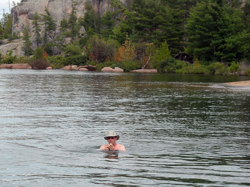 Photo: swimmer with hat, sunglasses, and camera; shoreline of South Benjamin Island in background