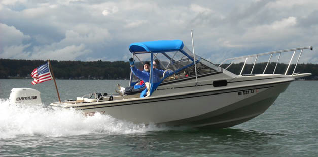 Photo: E-TEC powered boat on plane with your author at the helm during propeller testing.